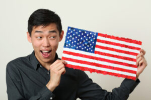 Young Asian student showing US national flag and looking sideway